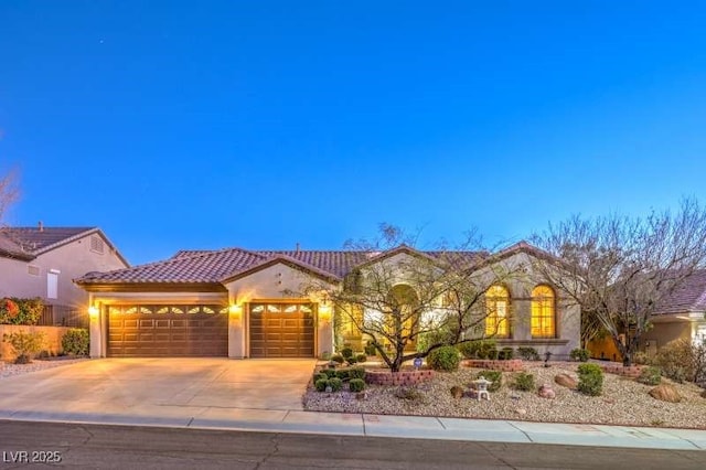 mediterranean / spanish-style house with a garage, driveway, a tile roof, and stucco siding