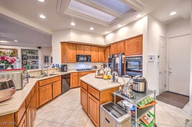 kitchen with brown cabinets, light countertops, a sink, a peninsula, and black appliances