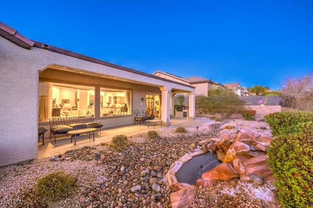 rear view of house with a patio area, fence, and stucco siding