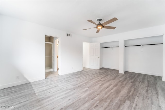 unfurnished bedroom with baseboards, light wood-style flooring, and multiple closets