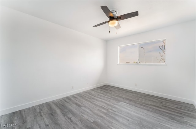 empty room featuring ceiling fan, baseboards, and wood finished floors