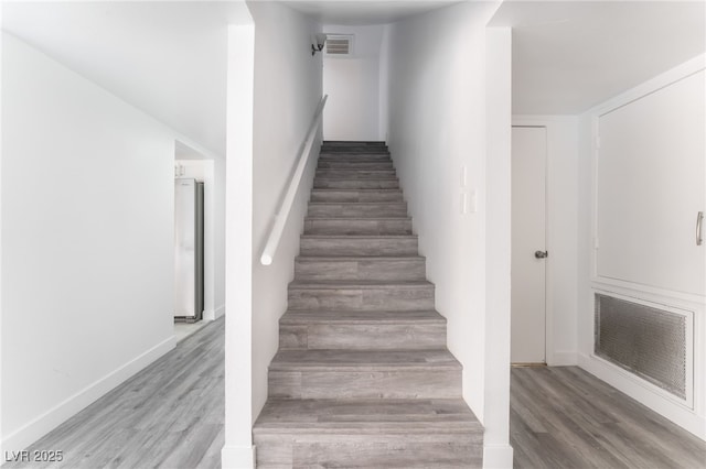 stairway featuring wood finished floors, visible vents, and baseboards