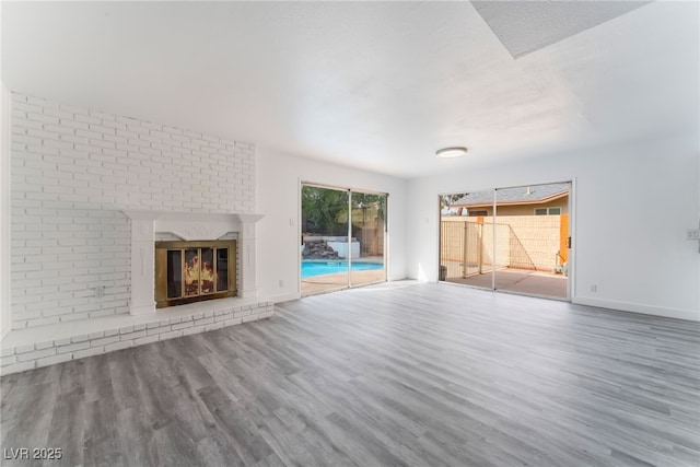 unfurnished living room with a fireplace, baseboards, and wood finished floors