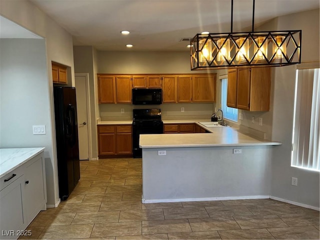 kitchen with a sink, black appliances, light countertops, and pendant lighting