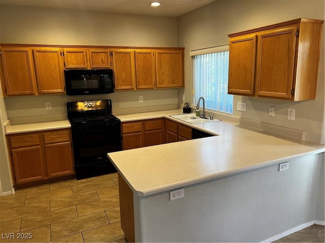 kitchen featuring light countertops, a sink, a peninsula, and black appliances