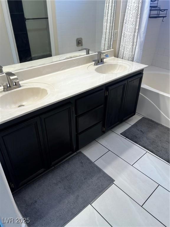 bathroom featuring double vanity, shower / tub combo, tile patterned flooring, and a sink