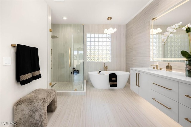 full bath featuring tile patterned flooring, a shower stall, tile walls, a freestanding bath, and vanity