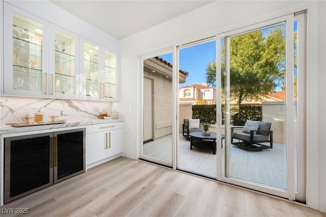 entryway with light wood-style floors, beverage cooler, and a bar