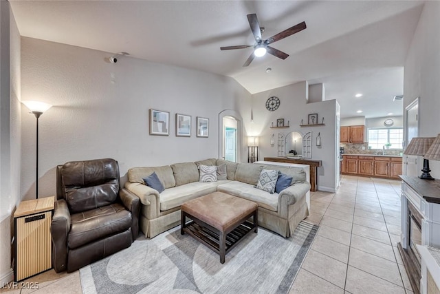 living room with light tile patterned floors, arched walkways, a ceiling fan, vaulted ceiling, and radiator