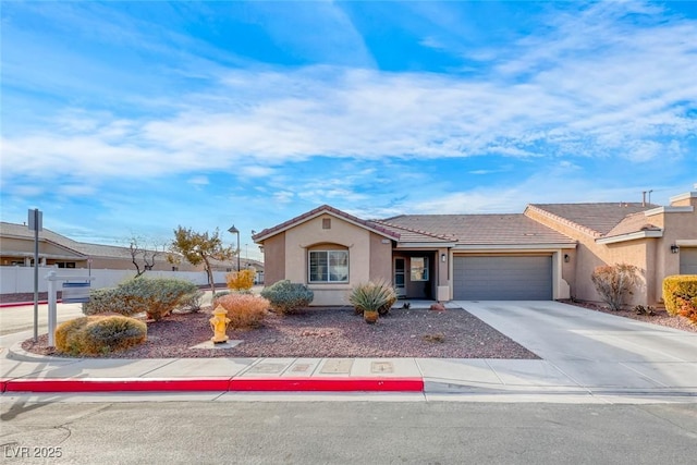 view of front facade featuring a garage, concrete driveway, a tiled roof, and stucco siding