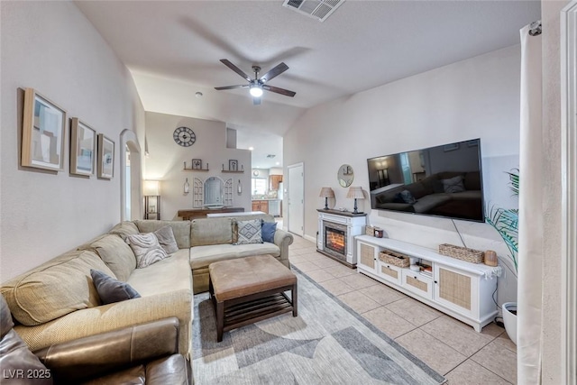 living area with arched walkways, light tile patterned floors, visible vents, ceiling fan, and vaulted ceiling