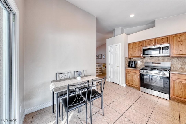 kitchen with light tile patterned flooring, stainless steel appliances, baseboards, light countertops, and tasteful backsplash