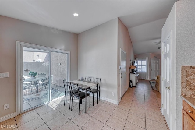 dining space featuring lofted ceiling, light tile patterned flooring, and baseboards