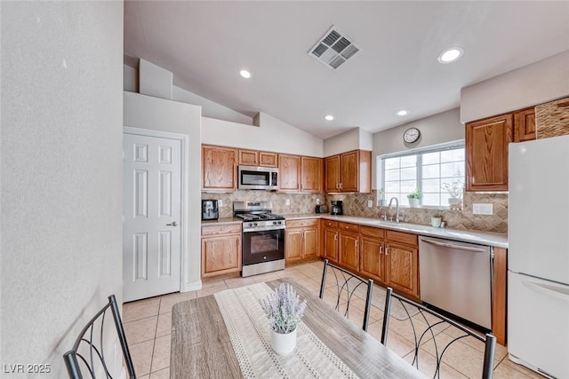 kitchen with light countertops, appliances with stainless steel finishes, visible vents, and tasteful backsplash