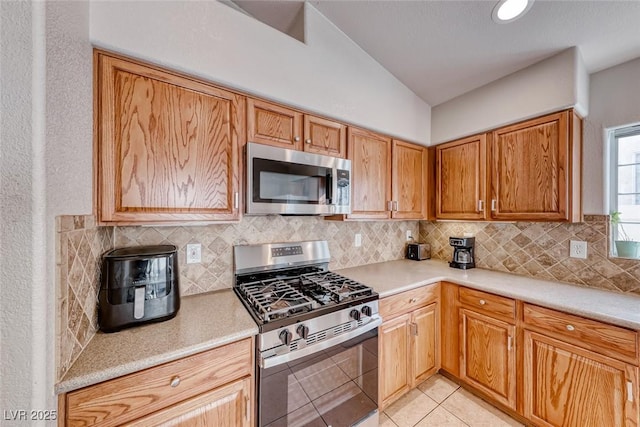 kitchen featuring light tile patterned floors, tasteful backsplash, appliances with stainless steel finishes, and light countertops