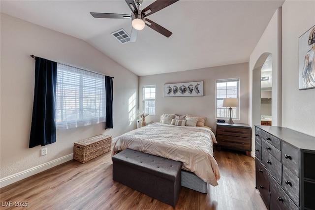 bedroom with lofted ceiling, visible vents, baseboards, and wood finished floors