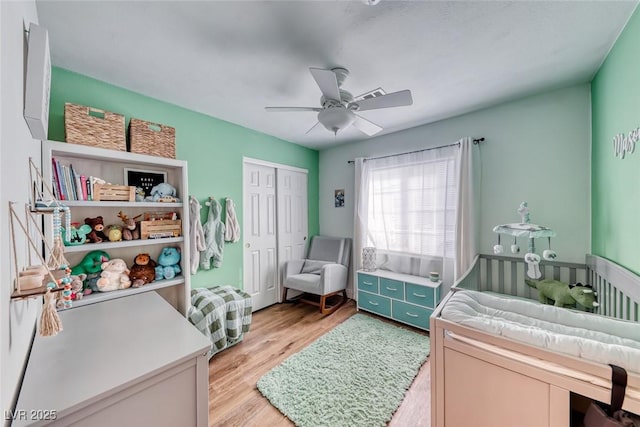 bedroom with light wood finished floors, ceiling fan, and a closet