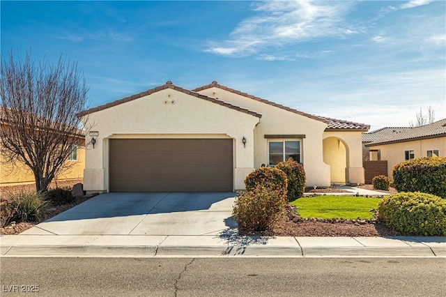 mediterranean / spanish-style house with concrete driveway, a tiled roof, an attached garage, and stucco siding