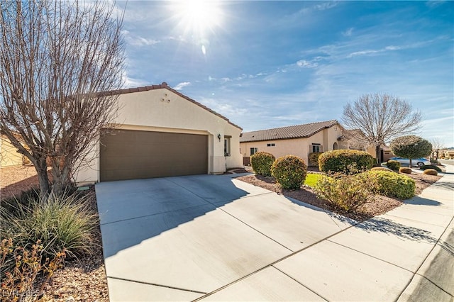 mediterranean / spanish-style home featuring concrete driveway, a tiled roof, an attached garage, and stucco siding