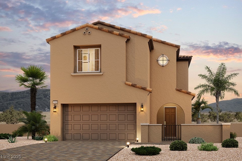 mediterranean / spanish home featuring decorative driveway, a tile roof, stucco siding, fence, and a garage