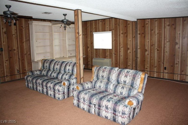 carpeted living area featuring a ceiling fan, a wall mounted air conditioner, wood walls, and a textured ceiling