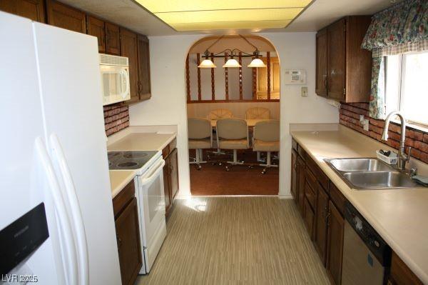 kitchen with light wood-style floors, white appliances, light countertops, and a sink