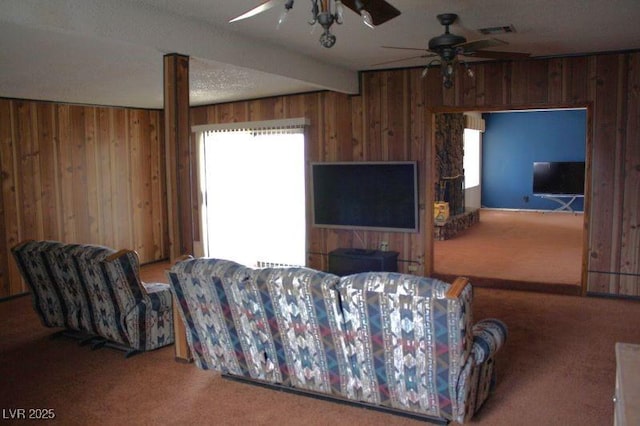 living area featuring beam ceiling, wooden walls, visible vents, and carpet flooring