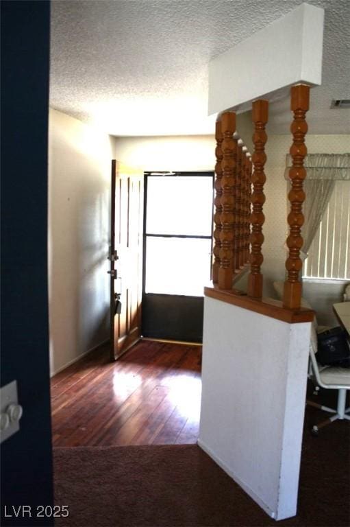 hallway featuring dark wood-style floors, stairs, visible vents, and a textured ceiling