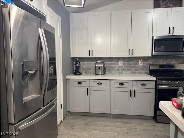 kitchen featuring wood finish floors, white cabinetry, stainless steel appliances, light countertops, and decorative backsplash