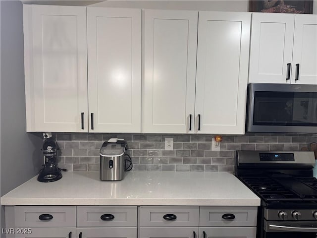 kitchen featuring light countertops, white cabinets, backsplash, and appliances with stainless steel finishes