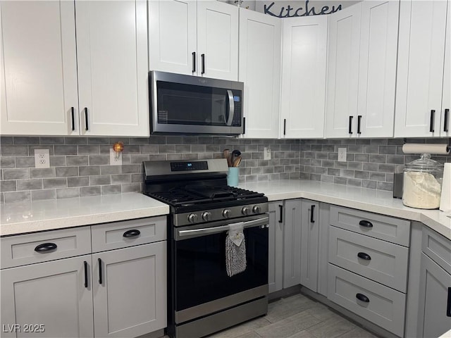 kitchen with decorative backsplash, gray cabinets, stainless steel appliances, and light countertops