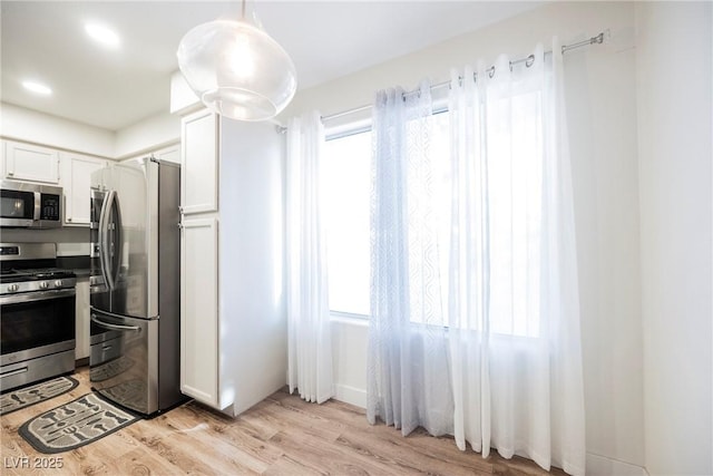 kitchen with light wood-style flooring, white cabinets, and stainless steel appliances