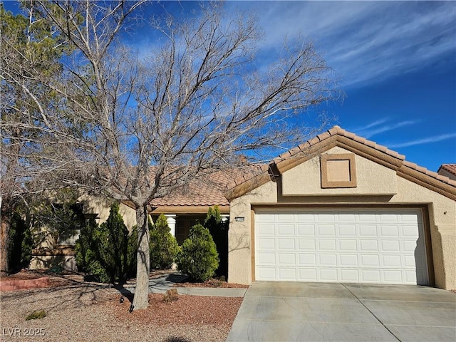 view of front of property with a garage, a tile roof, driveway, and stucco siding