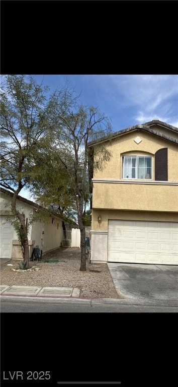 view of front of property with driveway, fence, an attached garage, and stucco siding