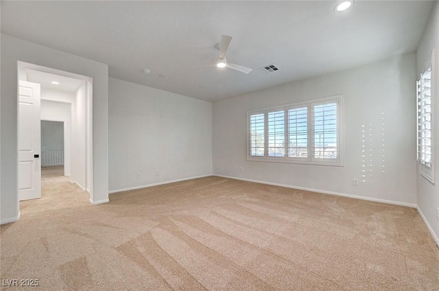 empty room with light colored carpet, visible vents, ceiling fan, and baseboards