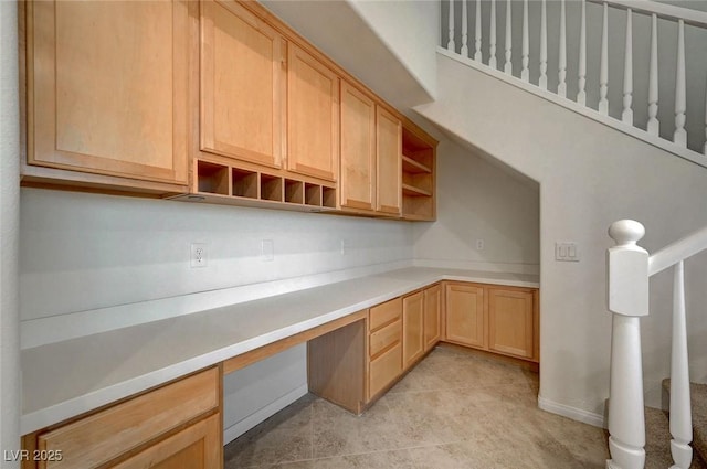 kitchen featuring open shelves, light brown cabinetry, light countertops, and built in study area