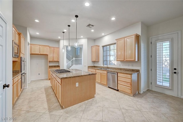 kitchen featuring stone counters, stainless steel appliances, a kitchen island, light brown cabinetry, and decorative light fixtures