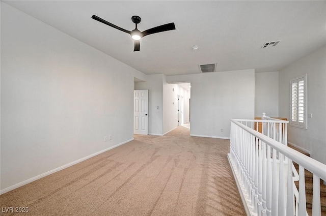 unfurnished room featuring light carpet, ceiling fan, visible vents, and baseboards