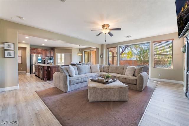 living room with baseboards, plenty of natural light, and light wood-style floors