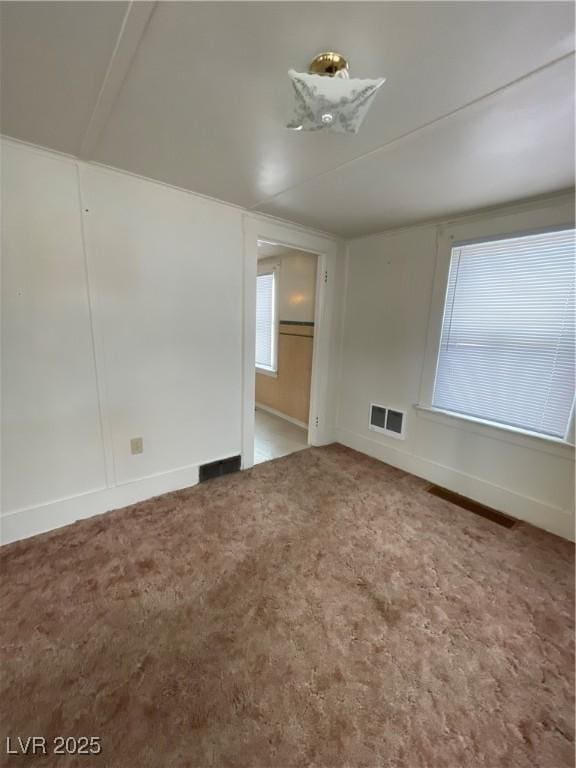 carpeted empty room featuring visible vents and baseboards