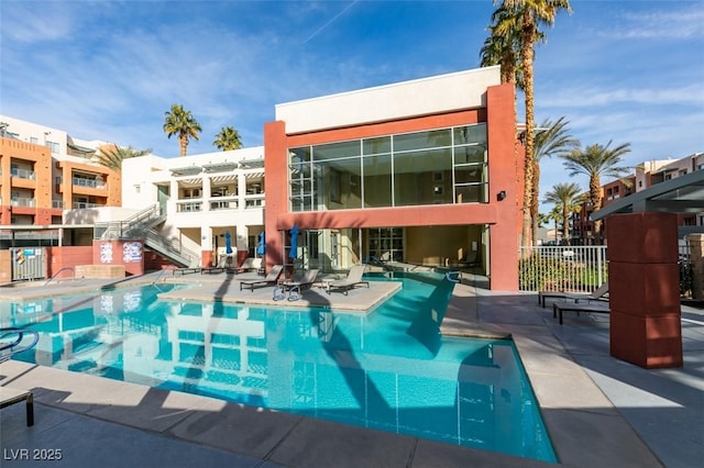 community pool with a patio area and fence