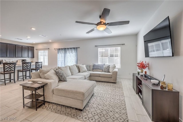 living room with light wood-type flooring, plenty of natural light, a ceiling fan, and recessed lighting