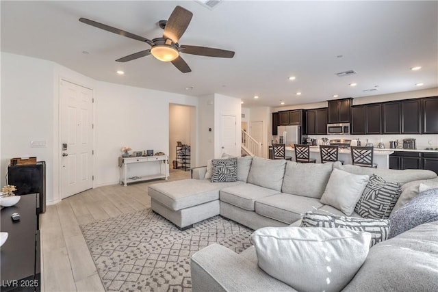 living area with recessed lighting, visible vents, baseboards, stairs, and light wood-type flooring