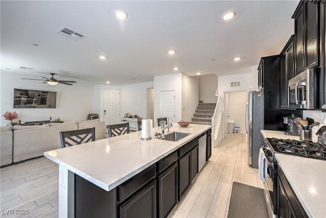 kitchen featuring a kitchen island with sink, visible vents, stainless steel appliances, and a sink