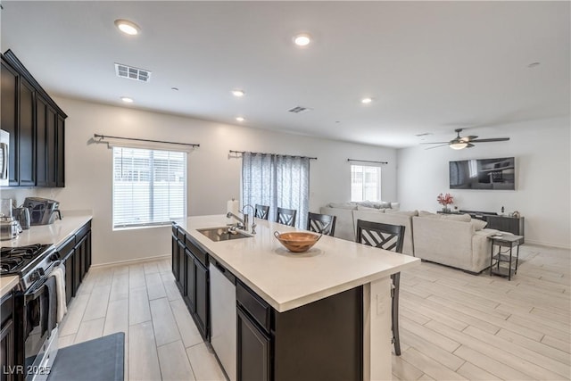 kitchen featuring stainless steel appliances, a breakfast bar, a sink, visible vents, and light countertops