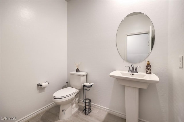 half bathroom featuring baseboards, a sink, and toilet