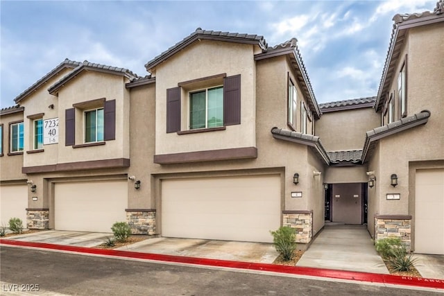 multi unit property with a garage, stone siding, and stucco siding