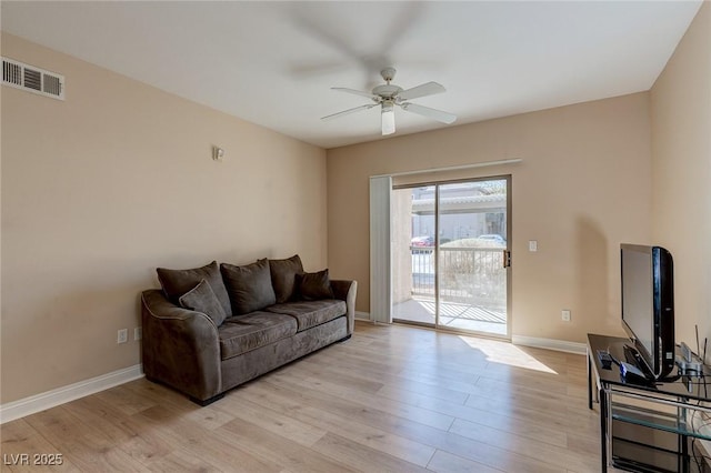 living room featuring a ceiling fan, visible vents, light wood-style flooring, and baseboards