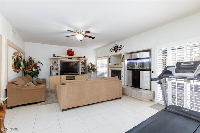 living room featuring ceiling fan, light tile patterned floors, a fireplace, and visible vents