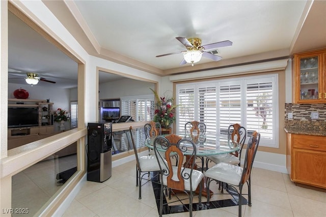 dining area with baseboards, light tile patterned floors, a ceiling fan, and a healthy amount of sunlight